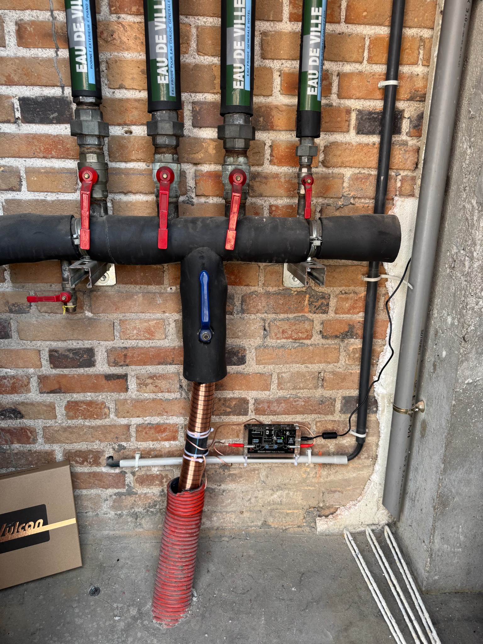 VULCAN 5000 installé à l’Auberge du Cheval Blanc à Yvoy-le-Marron, avec le boîtier électronique et ses bandes de cuivre autour de la canalisation